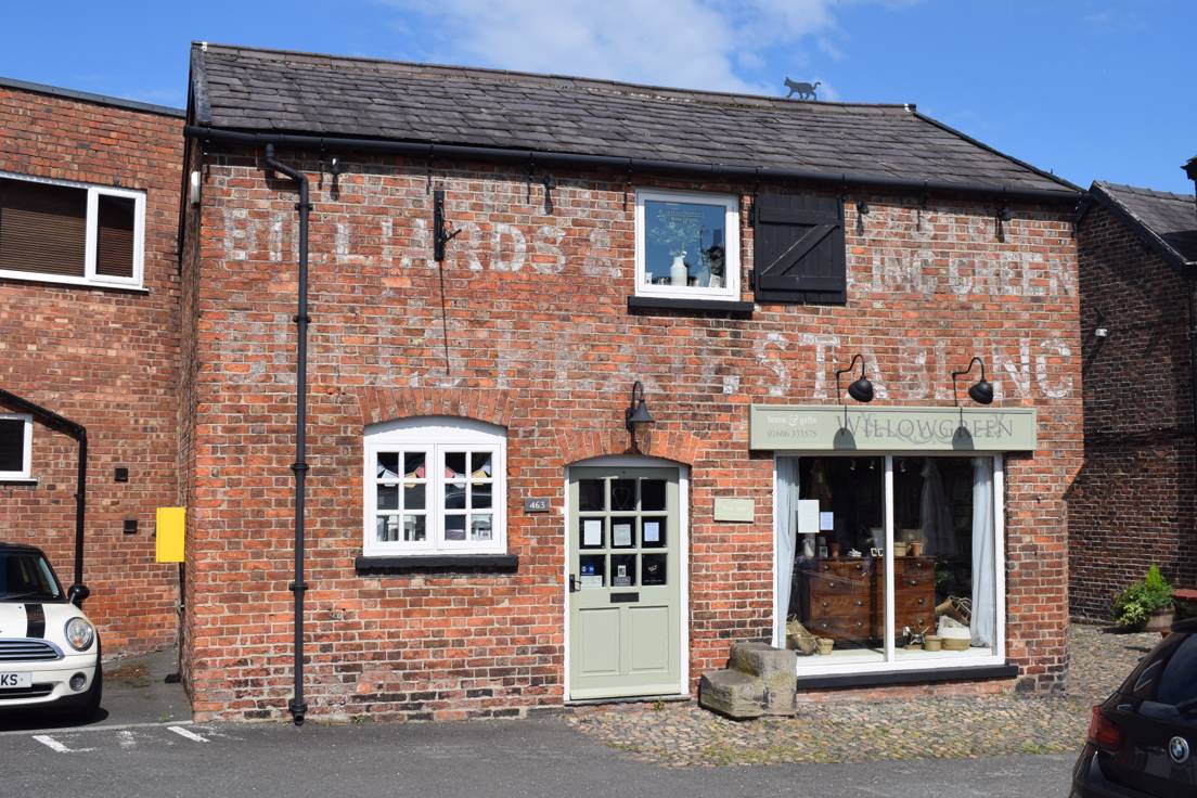 Two storey brick stable building with ghost signs advertising stabling, billiards and a bowling green