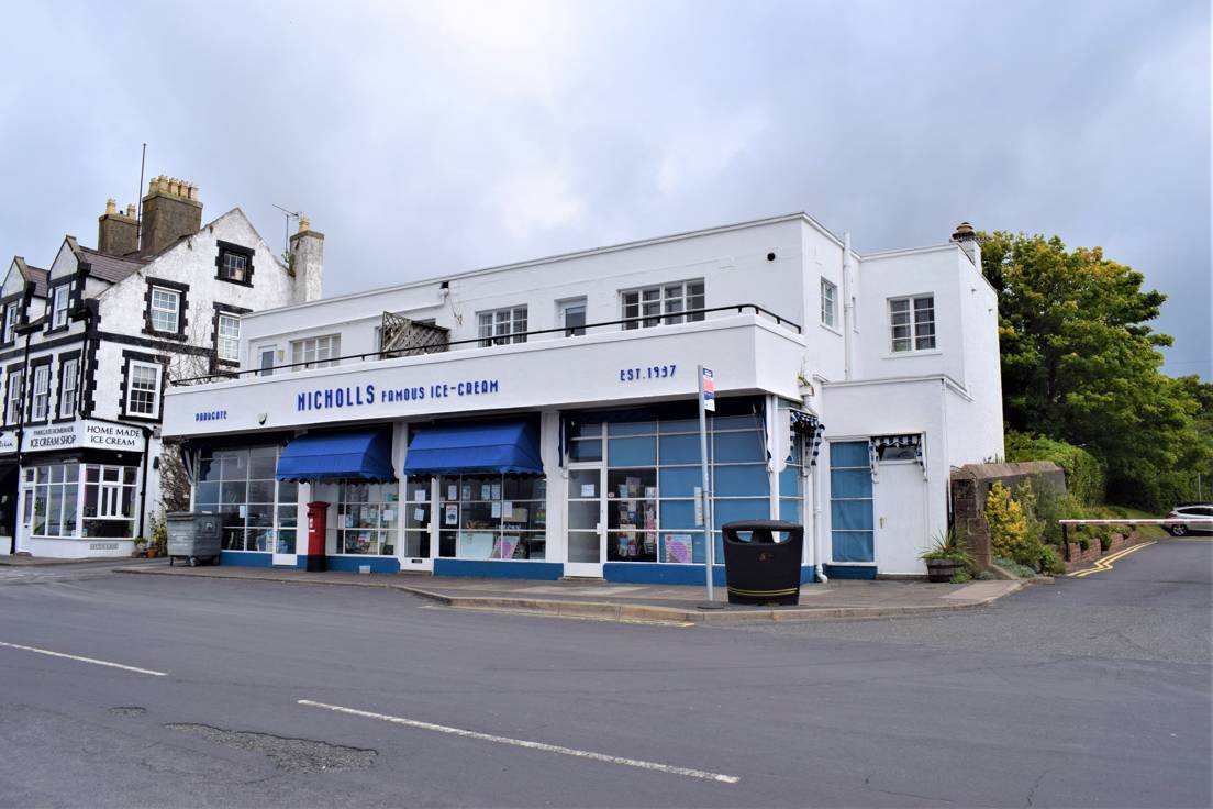 A white 1930s building with blue fittings and blue writing on the front which reads Parkgate Nicholls Famous Ice Cream Established 1937